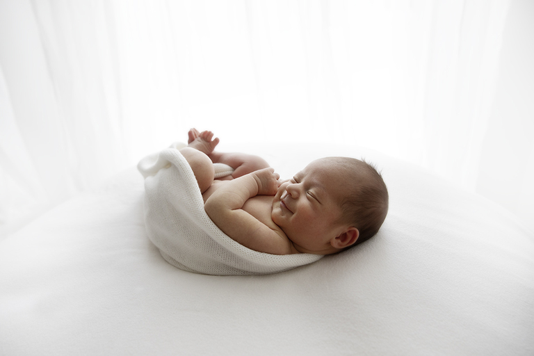 newborn photographer of smiling baby white background